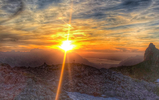 view from a mountains pass, lake in the distance, in the evening sun, with cross